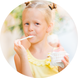 A young girl enjoying a scoop of ice cream, looking content while holding a spoon and a small bowl.